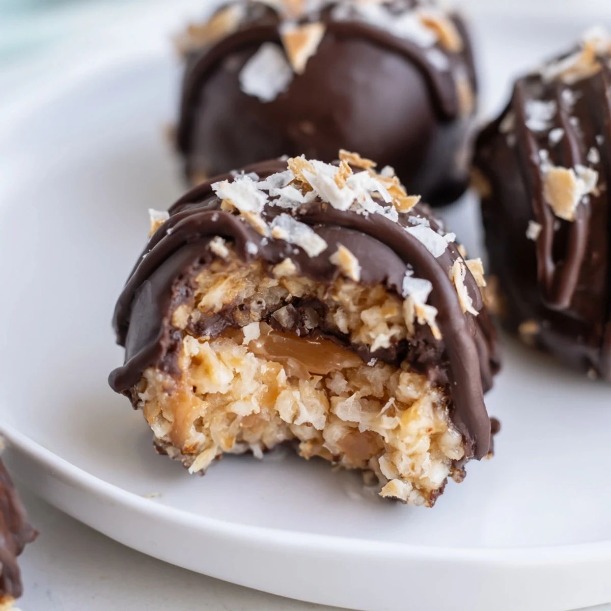 Chocolate-dipped no bake Samoa bites arranged on parchment with sticky caramel coconut topping