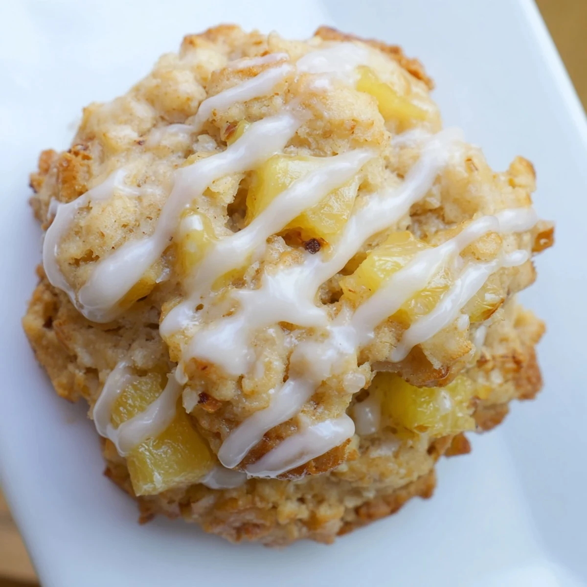 Stack of moist pineapple cookies drizzled with white glaze on a baking sheet
