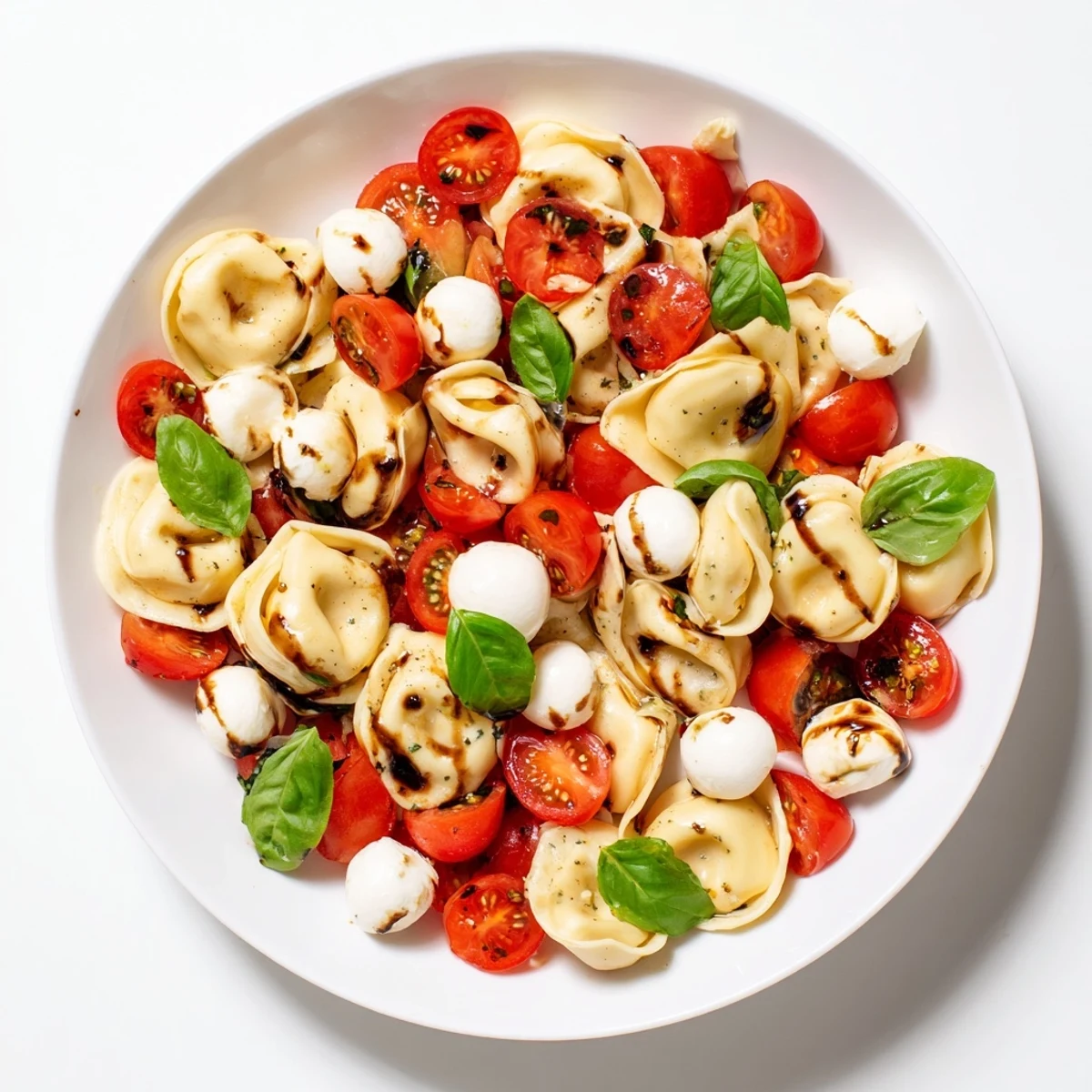 Fresh Italian pasta salad featuring cheese tortellini, halved cherry tomatoes, and creamy bocconcini in herb dressing