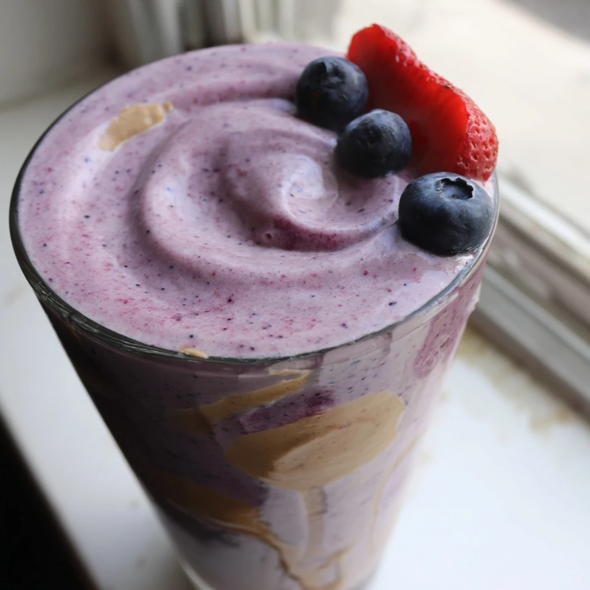 Creamy peanut butter berry smoothie poured into a mason jar with scattered berries