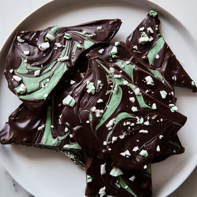 Rich Mint Chocolate Bark with White Chocolate Swirl broken into rustic shards on a dark slate platter, perfect with a cup of coffee.